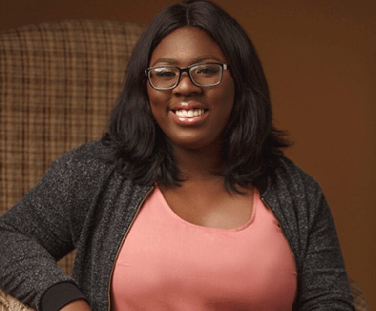 A woman wearing a pink top, smiling at the camera